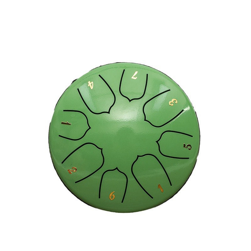 A green steel pan drum with black engraved finger holes and gold-colored numbers marking the notes, shown on a plain white background.
