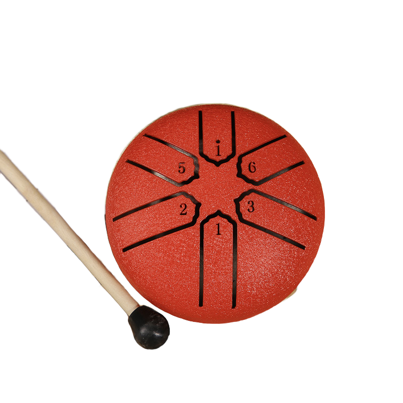 A steel pan drum with a textured orange-red body, black numbered metal tongues, and a wooden mallet with a black rubber tip, shown on a plain white background.