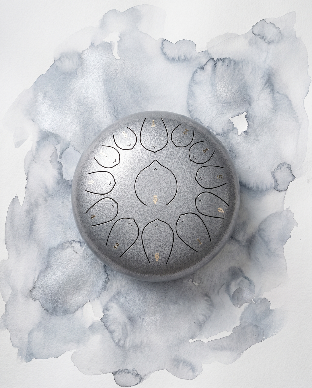 `Silver Ethereal 12-inch steel tongue drum with numbered notes beneath an ethereal water color sky.